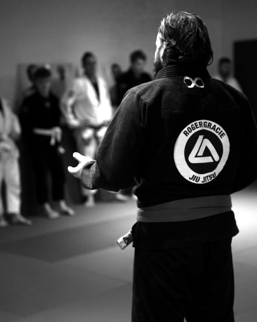 Coach in a black Roger Gracie gi teaching a class